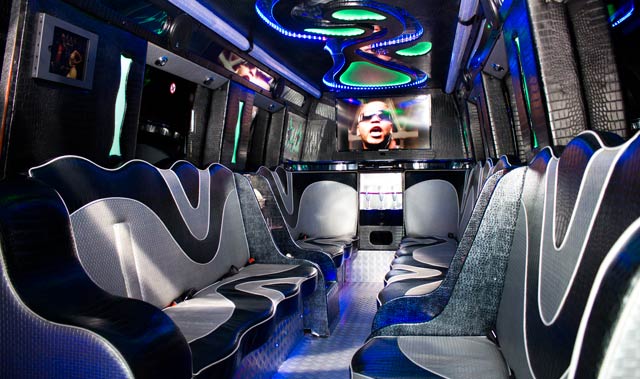 Party-bus interior with facing seats, screens and coloured ceiling lights